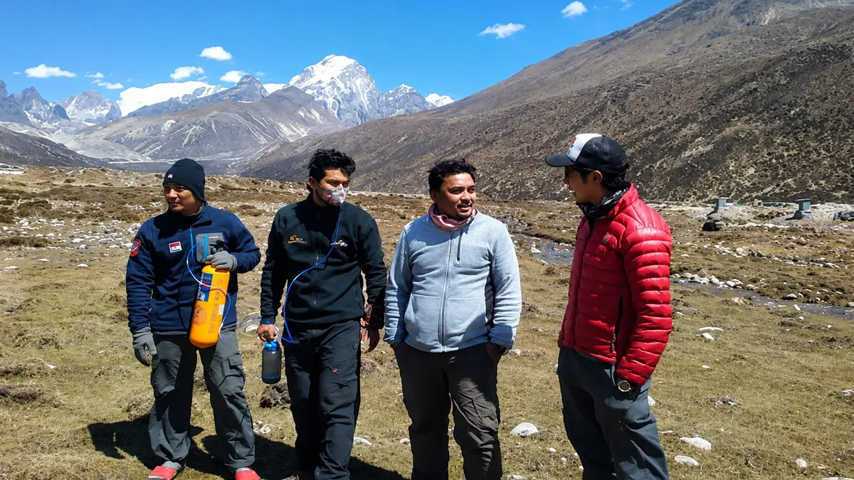 Trekking guides carrying portable oxygen cylinder for altitude sickness prevention on Everest Base Camp trek