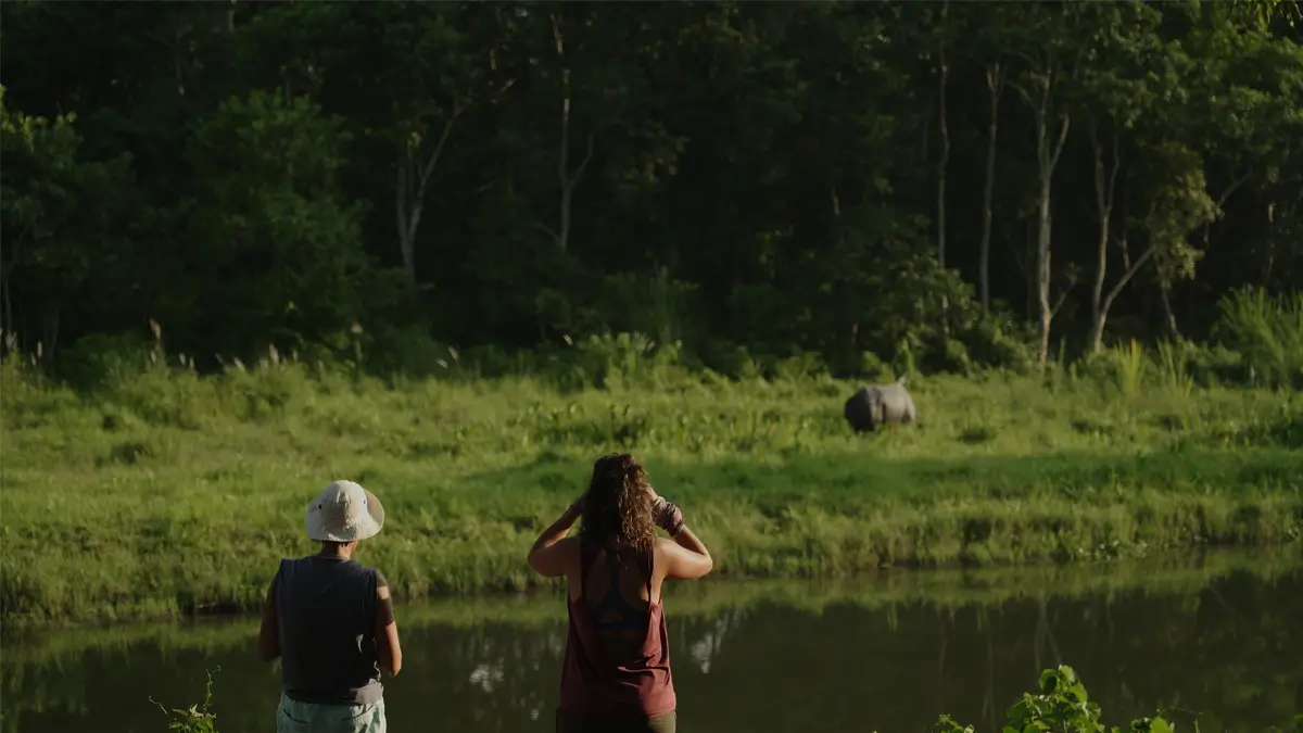 Visitors watching a one-horned rhino across the river in Chitwan National Park