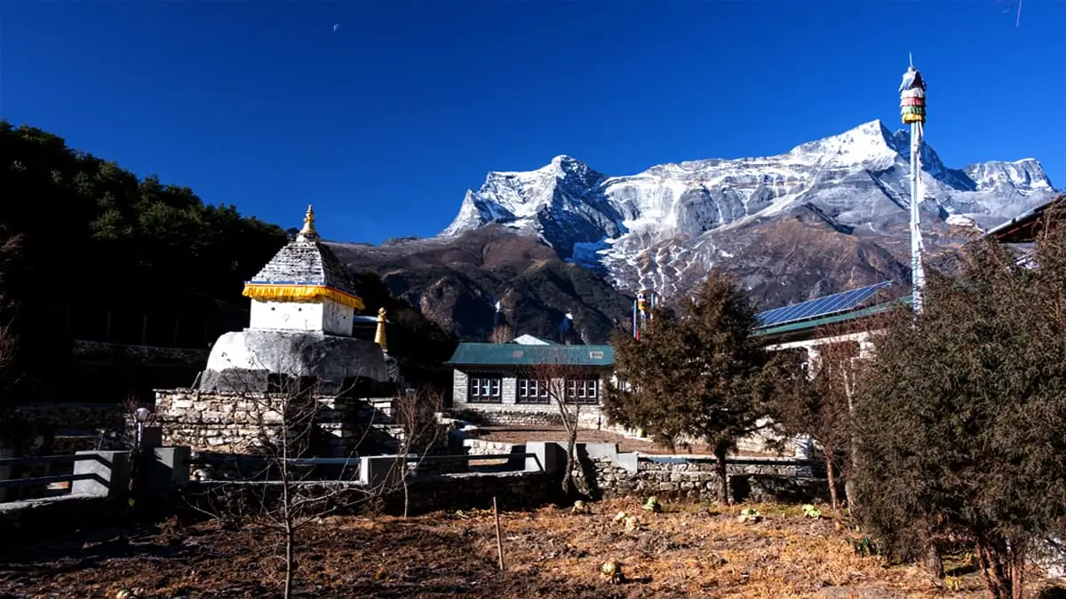Traditional Sherpa village stupa with snow-capped Himalayan peaks and blue sky Nepal