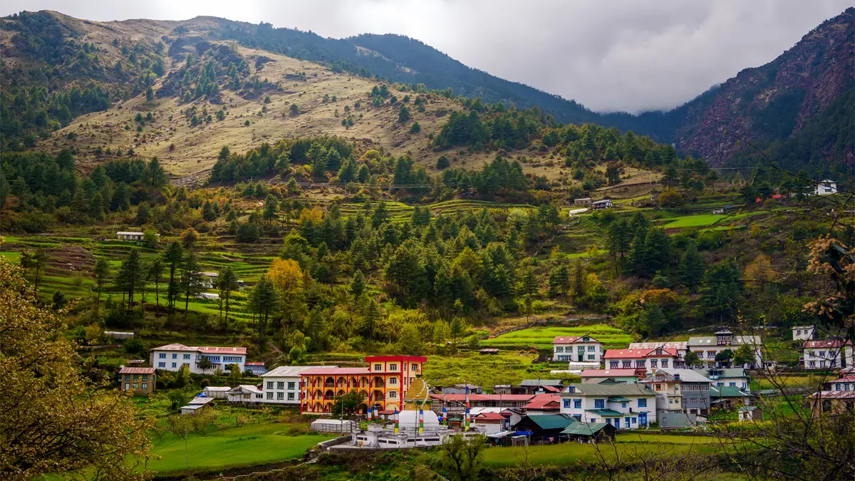 Junbesi village with stupa and red-yellow building among green hills