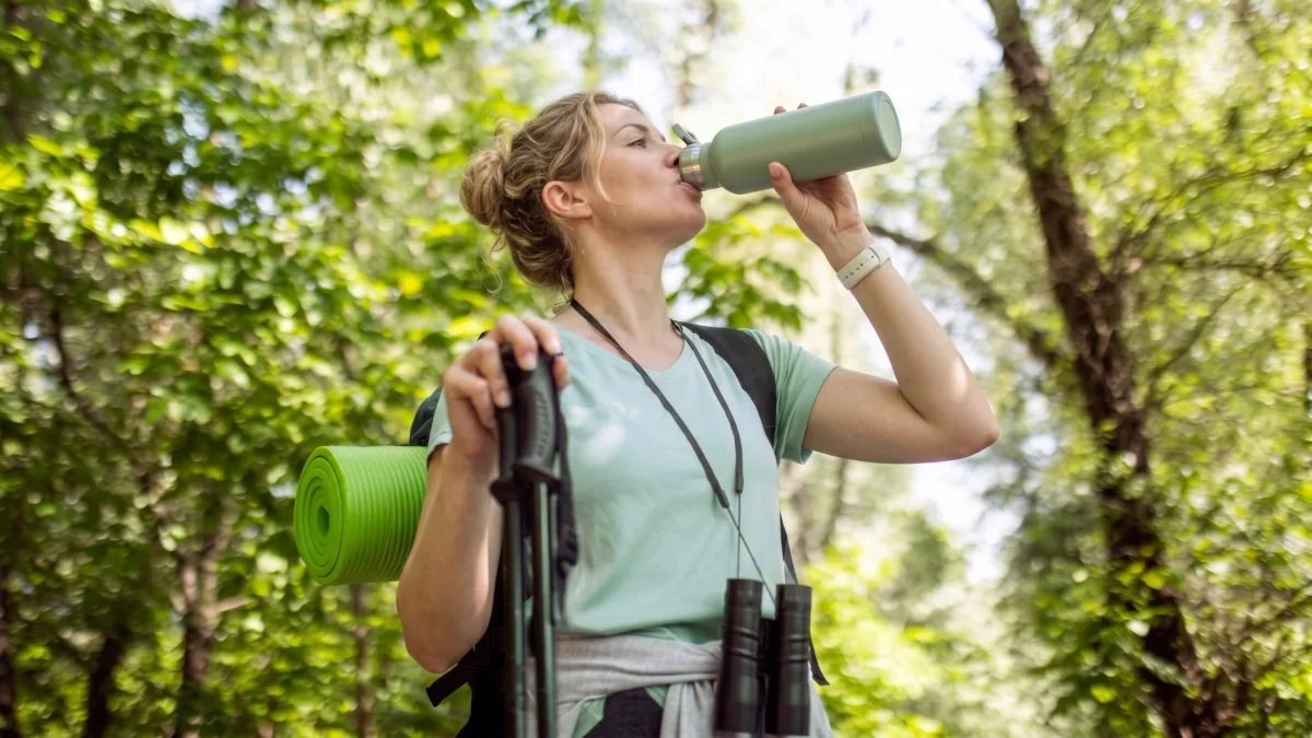 Trekker drinking water from a reusable bottle