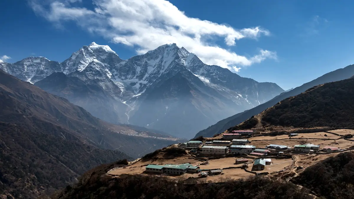Himalayan village on a ridge with snow-capped peaks under clear May skies in Nepal